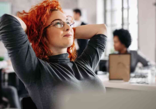 Woman With Curly Bright Red Hair Relaxing in a Chair in an Office